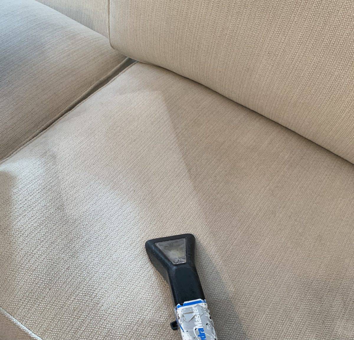Sofa cushion being steam cleaned, clean pass beside the soiled fabric